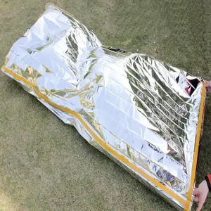 Close-up of silver thermal emergency sleeping bag made of PET aluminum film on grass