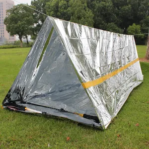 Reflective silver emergency tent with orange stripe set up on green grass outdoors.