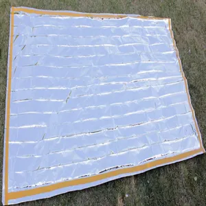 Foldable silver aluminum thermal emergency survival blanket spread on outdoor grass background
