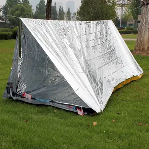 Outdoor emergency silver reflective tent for survival and thermal insulation on grass.
