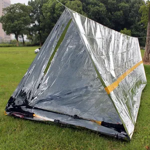 Emergency thermal PE shelter tent set up outdoors in a field using trekking poles