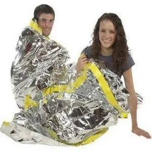 Thermal silver emergency sleeping bag demonstrated in a survival scenario by two people.