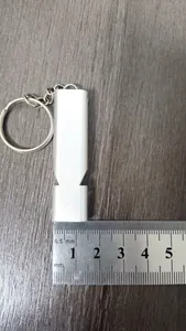Macro view of silver aluminum alloy dual-tube survival whistle with ruler for size reference