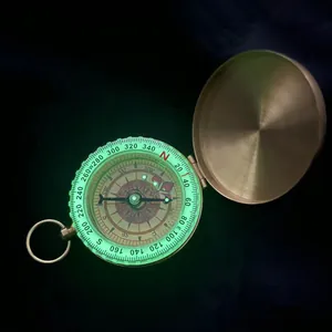 Primer plano de una brújula de latón vintage con una esfera luminosa verde brillante