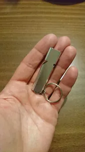 High-frequency silver aluminum alloy dual-tube survival whistle with keychain held in hand