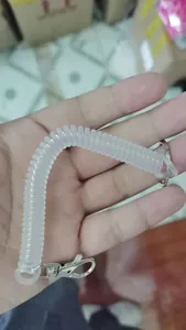 Gros plan d'un porte-clés à ressort en plastique élastique transparent tenu à la main