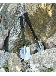 Two heavy-duty folding tactical shovels leaned against natural rocks for camping use.