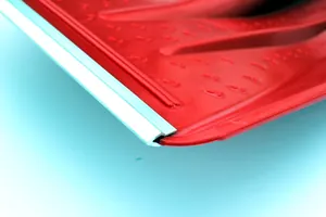 Primo piano della lama della pala da neve in plastica rossa con bordo rinforzato in metallo