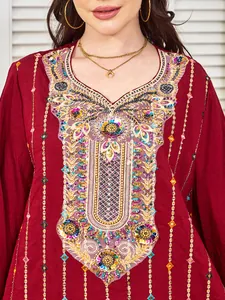 Détail de broderies multicolores et de paillettes sur une robe de soirée rouge ethnique