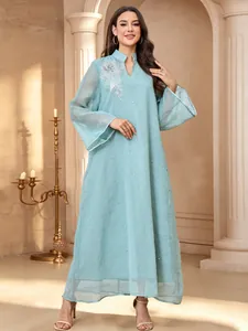 Gros plan d'une robe bleue avec d'élégantes broderies argentées et des strass étincelants.