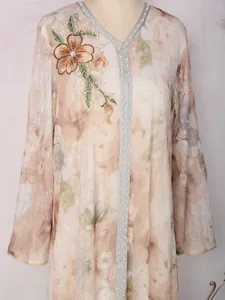 Détail d'une robe longue élégante avec broderies florales et strass scintillants raffinés