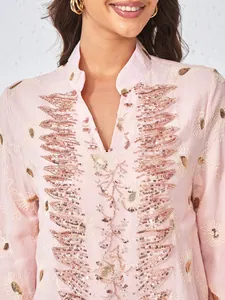 Primo piano del ricamo floreale e delle perline su un abito in rete rosa con scollo a V