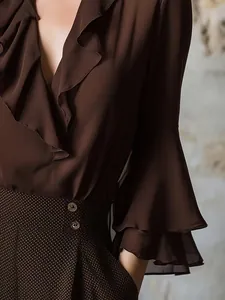 Primer plano de una blusa marrón chocolate con escote en V, volantes y mangas acampanadas