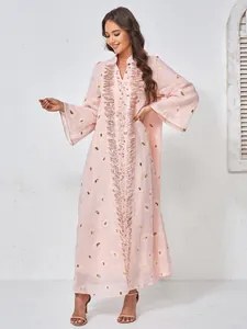 Dettaglio di un abito lungo in rete rosa con ricami floreali e decorazioni di perline