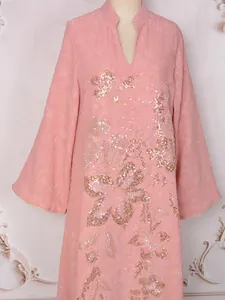 Détail d'une élégante robe longue rose avec motifs floraux en sequins et texture jacquard