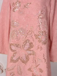 Détail d'une robe rose élégante avec broderies florales à paillettes complexes et tissu jacquard
