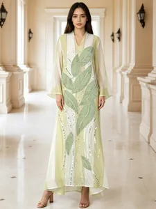 Elegante abito lungo con applicazioni di foglie e paillettes in verde tenue e bianco.