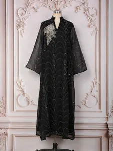 Détail d'une robe longue noire élégante avec strass argentés et motifs de perles