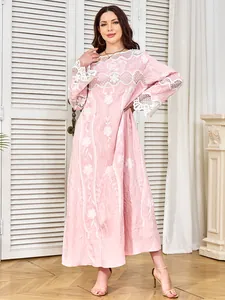 Detailed shot of an elegant pink maxi dress featuring white lace and embroidery.