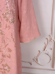 Gros plan d'une robe rose en jacquard avec une élégante broderie de fleurs en paillettes