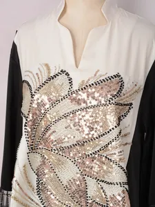 Gros plan d'une broderie ethnique à paillettes et perles sur une robe maxi patchwork bicolore.