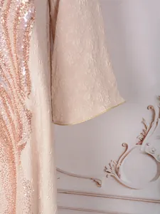 Detailed view of champagne evening gown featuring floral jacquard and rose gold sequins