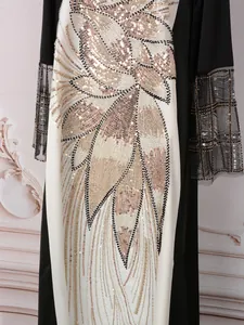 Détail d'une robe longue élégante avec motifs de feuilles en paillettes et manches en résille