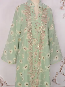 Vista dettagliata dell'abito in mesh verde menta con paillettes d'oro e ricami floreali.