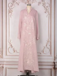 Détail de la broderie complexe de paillettes argentées et de perles sur la robe rose.