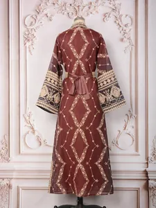 Back view of an elegant burgundy kaftan with intricate gold embroidery on a mannequin
