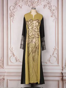 Vue détaillée des paillettes dorées et des perles sur une robe longue ethnique.