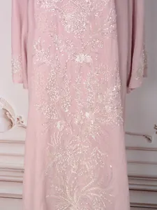 Détail macro d'une élégante robe ethnique rose avec broderie complexe de perles et paillettes