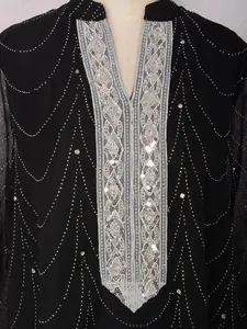 Gros plan de broderies de sequins et strass argentés sur une robe longue turque noire.