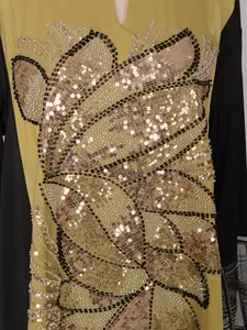 Détail de l'applique de paillettes et perles dorées sur une robe ethnique longue
