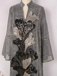 Gros plan de la broderie de fleurs en paillettes sur une robe grise de luxe à col montant