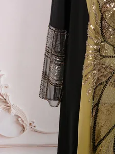 Détail des paillettes dorées et broderies perlées sur la manche d'une robe de style ethnique