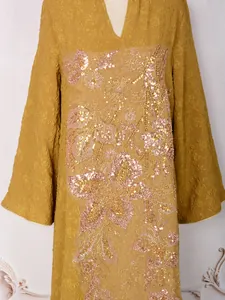 Détail de l'élégante broderie florale en paillettes dorées sur robe jaune moutarde