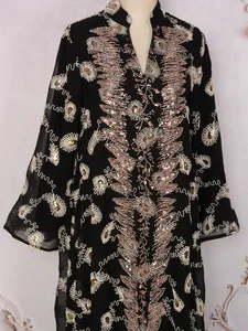 Dettaglio di un elegante abito in rete nera con intricati ricami dorati e perline