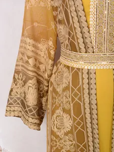 Detailed close-up of yellow Malaysian kaftan with intricate gold embroidery