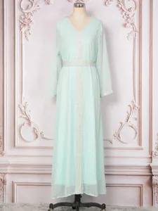 Longue robe caftan vert menthe avec détails bronzants argentés sur un mannequin de couture