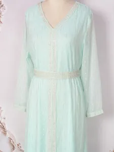 Robe caftan vert menthe élégante avec des paillettes argentées et rayures dorées.