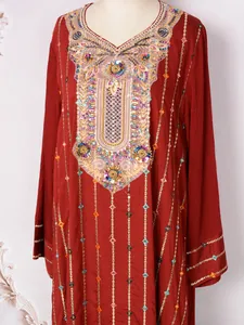 Détails de broderies multicolores et de paillettes sur une robe de soirée ethnique rouge