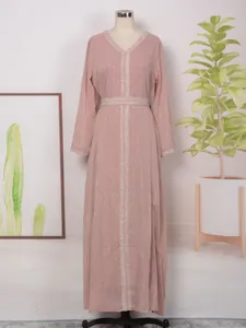 Détail d'une robe longue rose poudré avec des rayures bronzées et des perles.