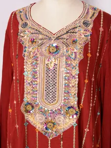 Gros plan sur les broderies dorées et les paillettes d'une élégante robe longue bordeaux.
