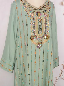 Gros plan sur les broderies élégantes d'une robe maxi verte de style ethnique.