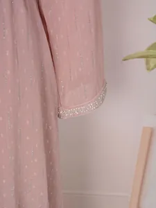 Vue rapprochée de la manche d'une robe rose avec rayures argentées et bordure perlée