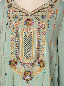 Détail des paillettes exquises et des broderies colorées sur une robe longue verte.