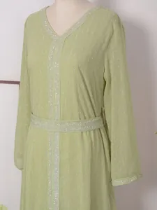 Vue détaillée d'une robe caftan longue vert clair avec d'élégants motifs rayés argentés.
