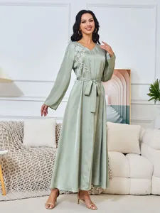 Elegante lichtgroene lange jurk met bloemenborduursels en een ceintuur in de taille.