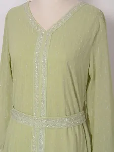 Gros plan d'une robe vert clair avec broderies de paillettes argentées et texture
